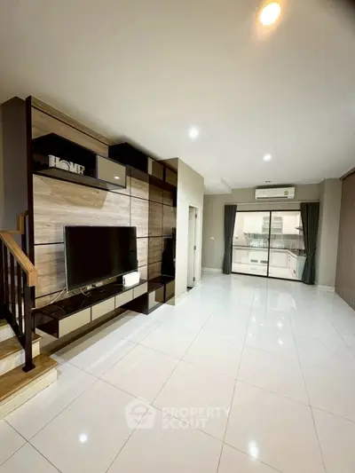 Spacious modern living room with sleek TV unit and large windows for natural light.