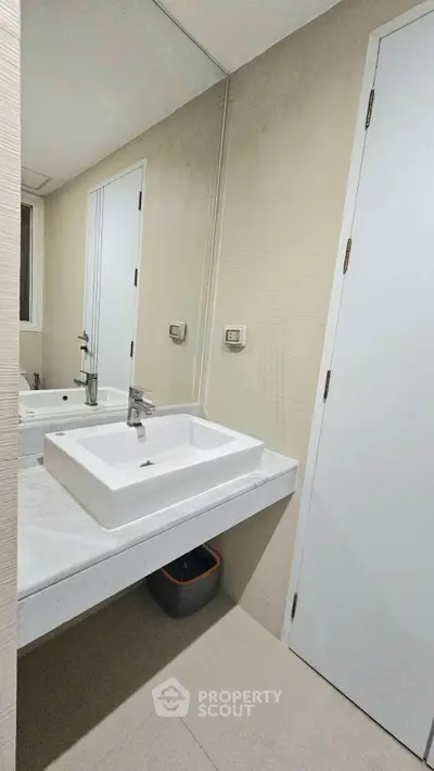 Modern bathroom with sleek sink and large mirror in a contemporary home.