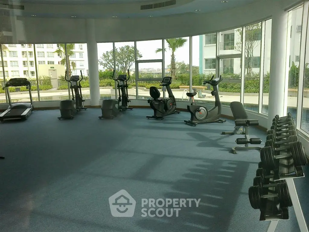 Spacious gym with modern equipment and large windows offering a scenic view.