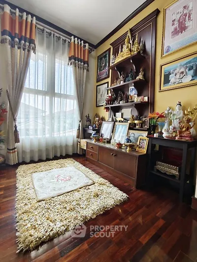 Charming living room with elegant decor and wooden flooring, featuring a cozy rug and large window for natural light.