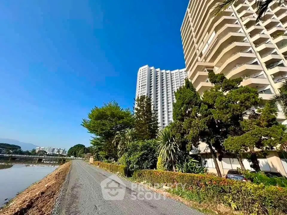 Stunning high-rise building with lush greenery and clear blue sky, offering serene living environment.