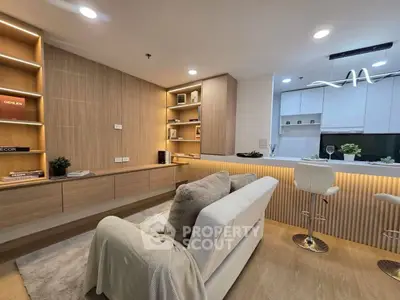 Modern living room with cozy sofa, stylish shelving, and sleek kitchen bar area