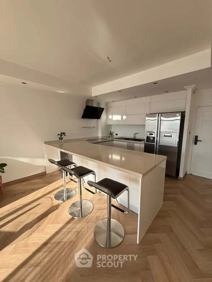Modern kitchen with sleek island and stainless steel appliances in bright, airy space.