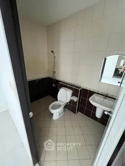 Compact bathroom with shower, toilet, and sink in a tiled setting.