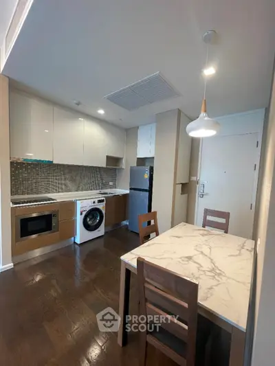 Modern kitchen with marble dining table and integrated appliances in a cozy apartment.