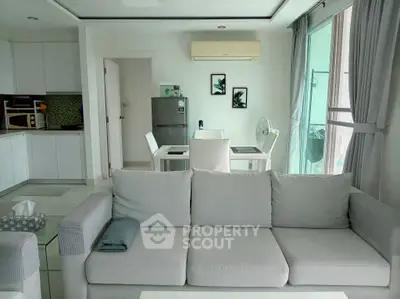 Modern living room with open kitchen, stylish decor, and natural light.