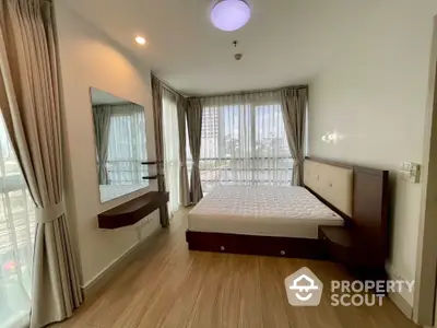 Spacious bedroom with large windows and modern furnishings in a high-rise apartment.