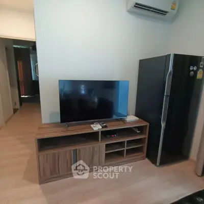 Modern living room with sleek TV stand and refrigerator, showcasing contemporary interior design.