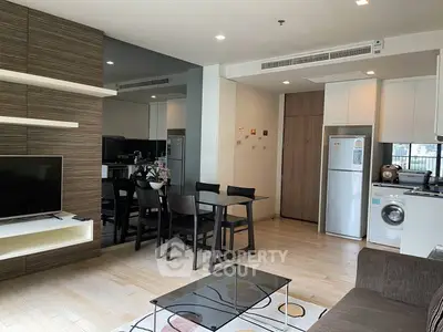 Modern open-plan living room with dining area, featuring sleek furniture and integrated kitchen appliances.