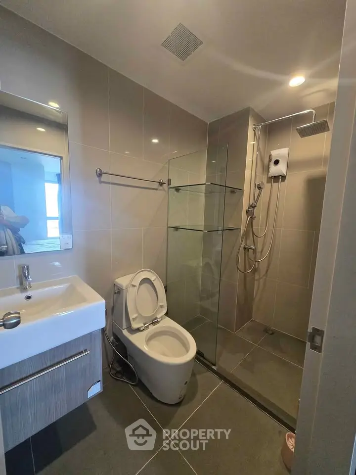 Modern bathroom with sleek fixtures and glass shower enclosure in a contemporary apartment.