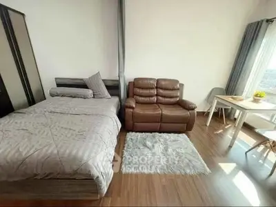 Cozy bedroom with modern decor, featuring a comfortable bed, leather sofa, and dining area with natural light.