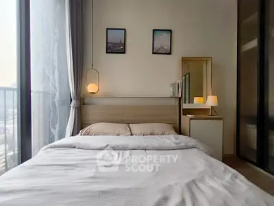 Cozy bedroom with modern decor and large window offering natural light.