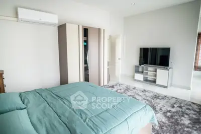 Spacious bedroom with modern amenities, large bed, plush carpeting, mirrored closet doors, and sleek entertainment unit.