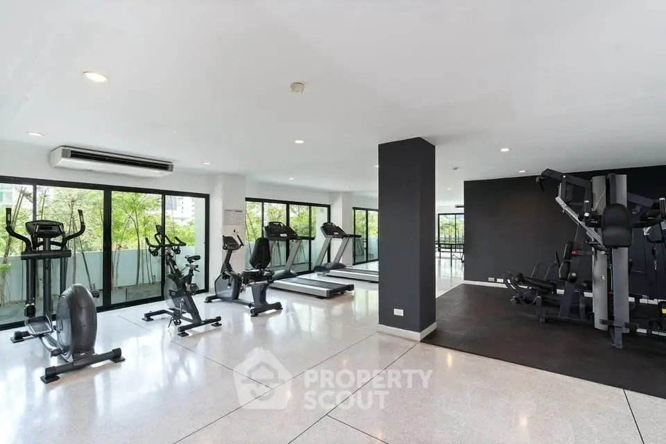 Spacious modern gym with state-of-the-art equipment and large windows offering scenic views.