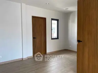 Spacious empty room with wooden doors and window, perfect for customization.