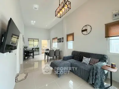Modern living room with stylish decor and open dining area, featuring a cozy sofa and wall-mounted TV.