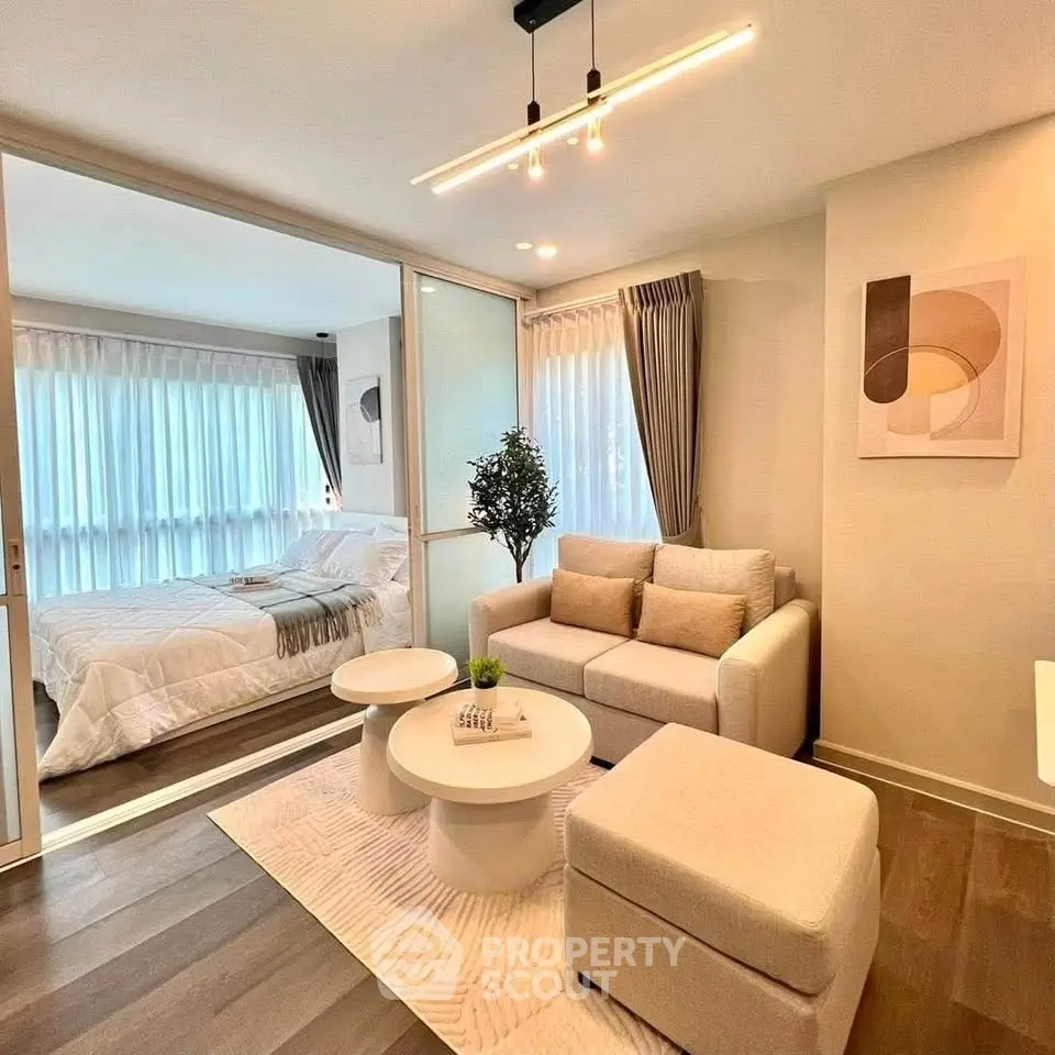 Modern living room with cozy seating and view into elegant bedroom, featuring stylish decor and natural light.