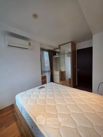 Spacious bedroom with modern air conditioning and wooden flooring