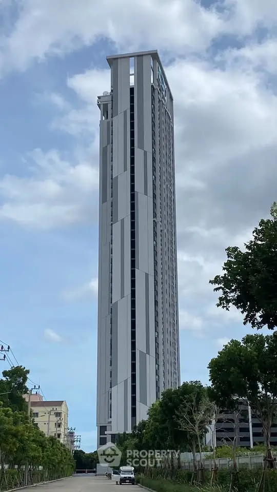 Stunning high-rise building with modern architecture and sleek design, surrounded by lush greenery and clear skies.