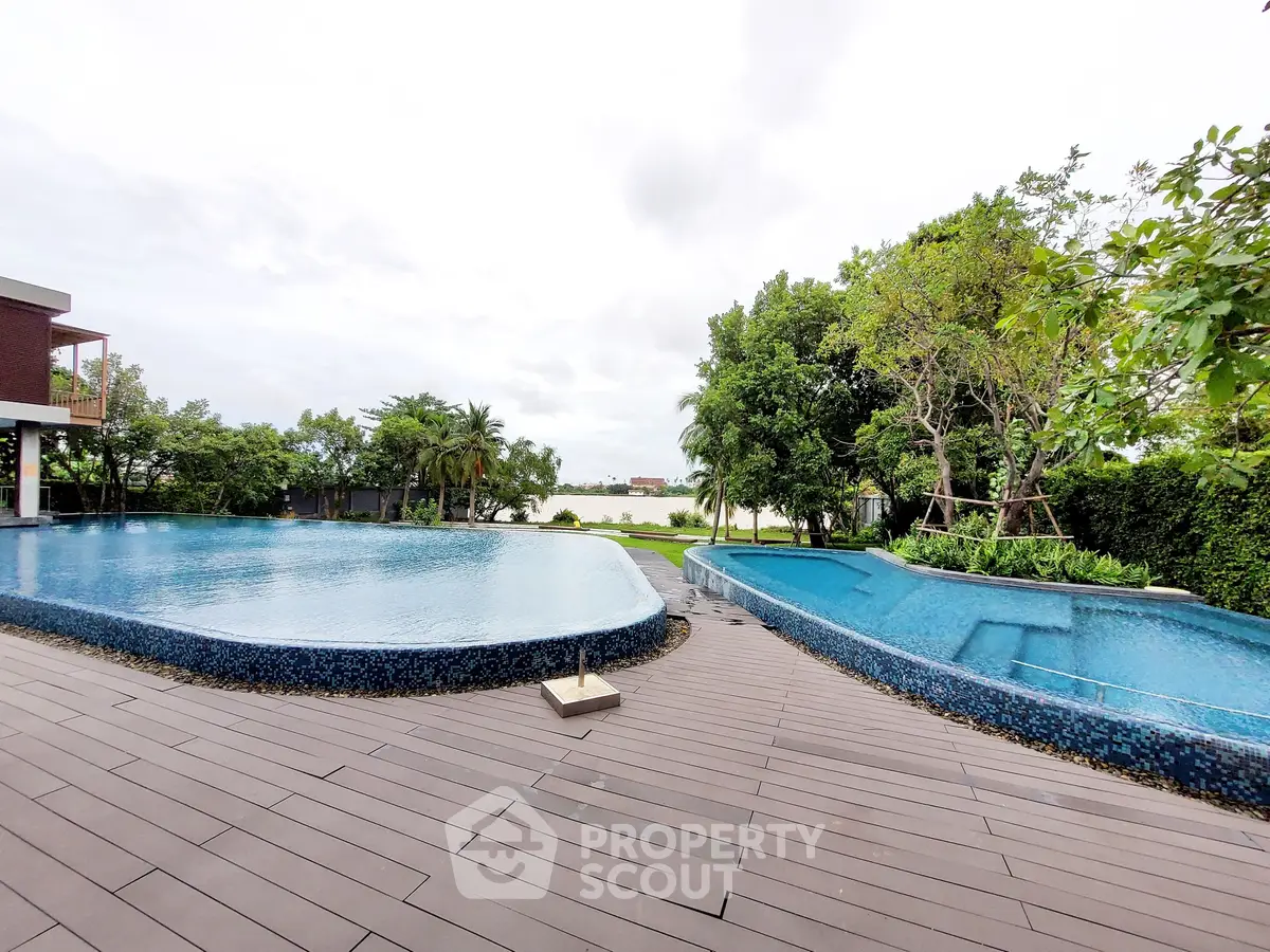 Luxurious outdoor pool area with lush greenery and serene water view, perfect for relaxation.