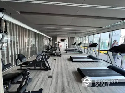 Modern gym with state-of-the-art equipment and large windows for natural light.