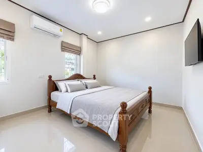 Spacious bedroom with elegant wooden bed and wall-mounted TV in modern home.