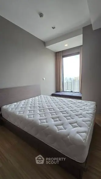 Spacious bedroom with large window offering city views and natural light.