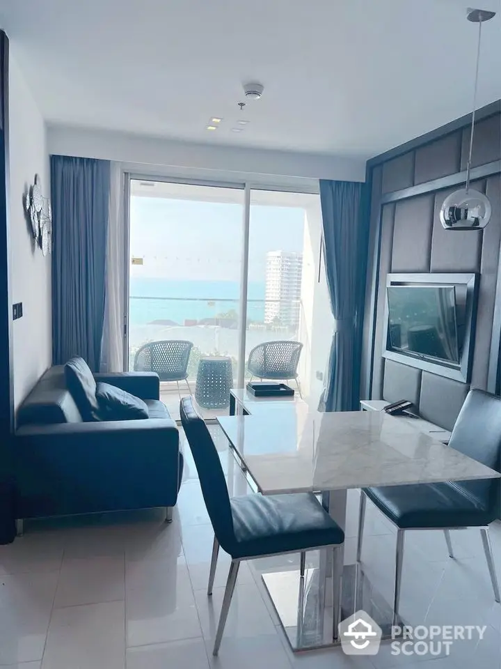 Modern living room with ocean view, sleek furniture, and large windows in a high-rise apartment.