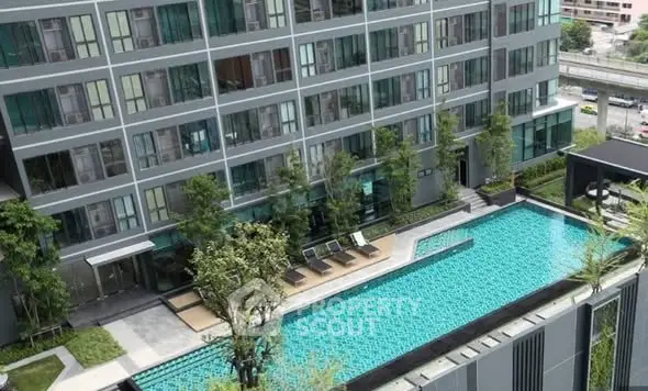 Modern condominium with a luxurious outdoor pool and lush greenery, offering a serene urban living experience.