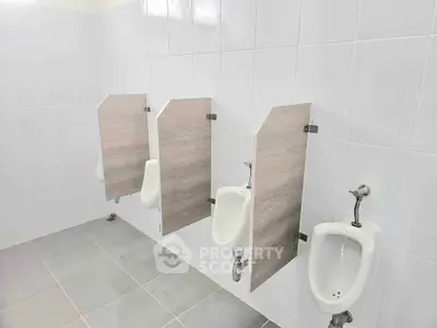 Modern restroom with sleek urinals and privacy partitions in a clean tiled environment.