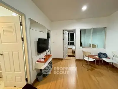 Modern living room with wooden flooring and wall-mounted TV in cozy apartment.