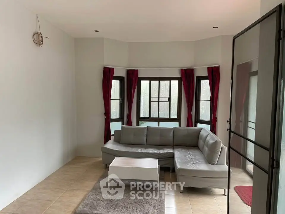 Spacious living room with modern gray sectional sofa and large windows.