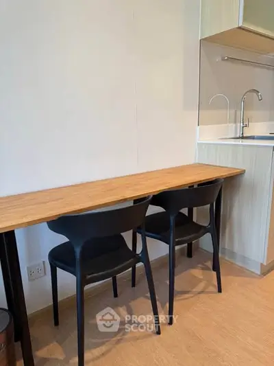 Modern kitchen with sleek wooden counter and stylish black chairs