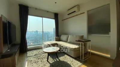 Modern living room with city view, cozy sofa, and natural light in urban apartment.