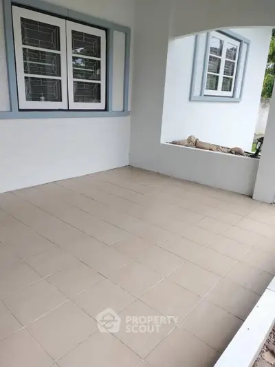 Charming tiled patio area with large windows and garden view, perfect for relaxation.