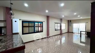 Spacious open-plan living room with large windows and marble countertops.