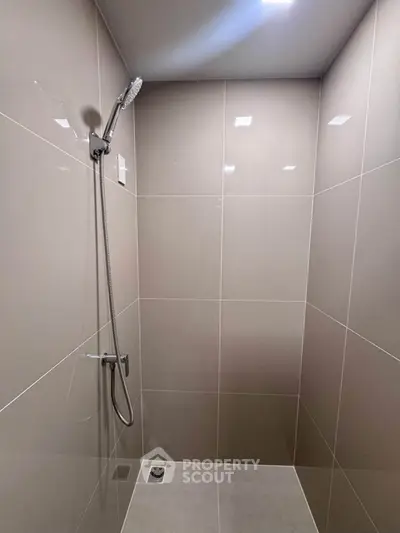 Modern minimalist shower area with sleek tiles and rainfall showerhead
