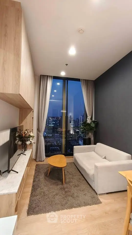 Modern living room with city view, featuring sleek furniture and floor-to-ceiling windows.