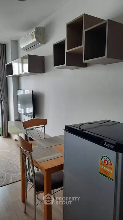 Modern living room with dining area and wall-mounted TV in stylish apartment.