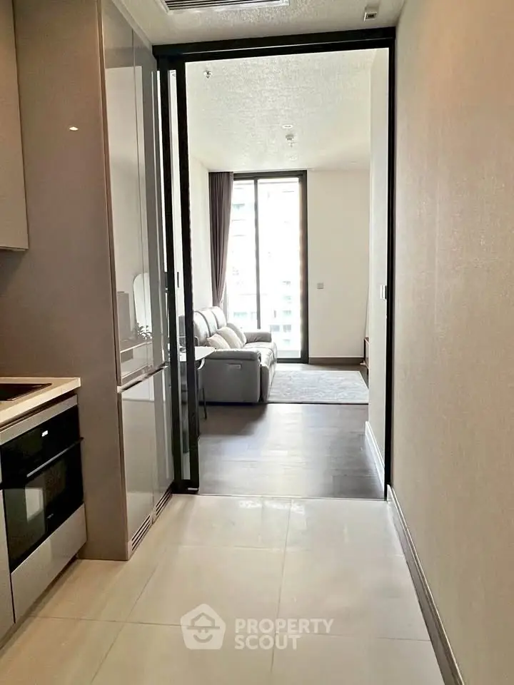 Modern apartment interior with sleek kitchen and cozy living room, featuring large windows for natural light.