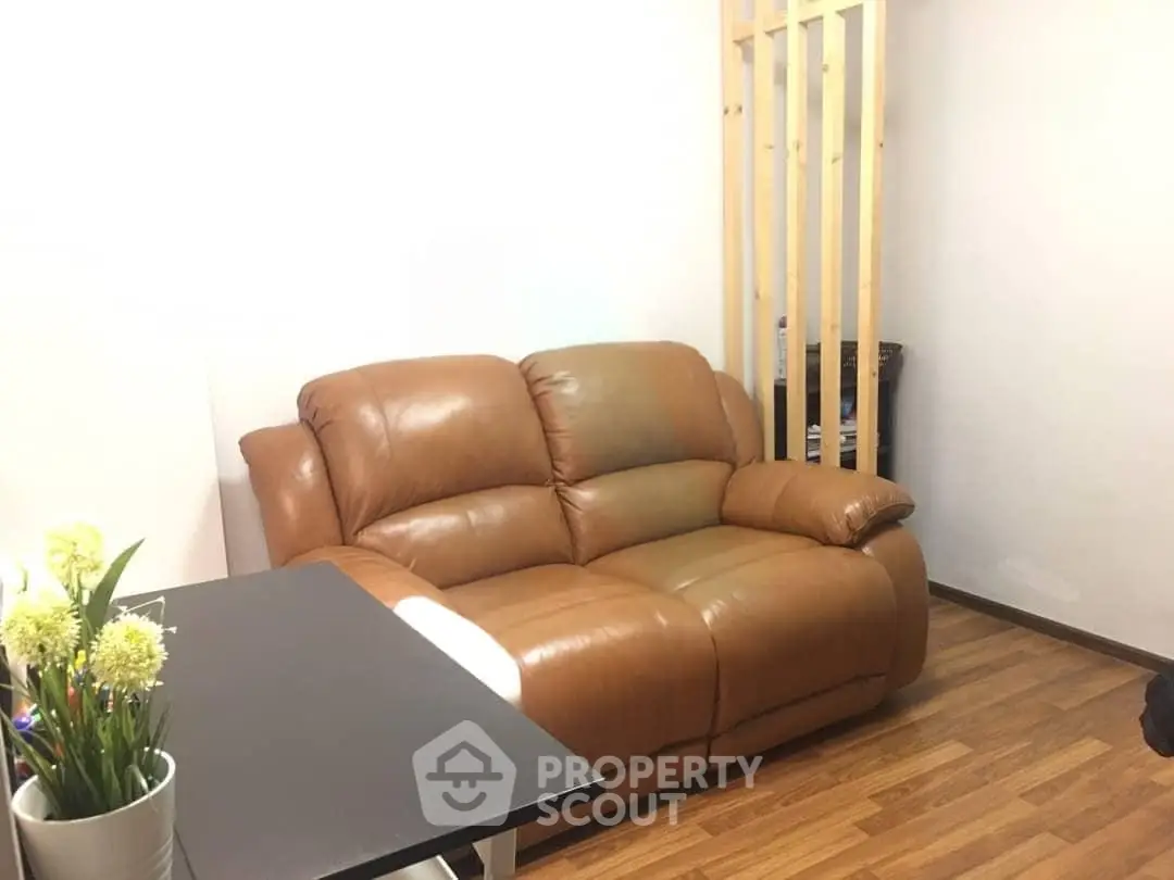 Cozy living room with brown leather sofa and wooden flooring, perfect for relaxation.