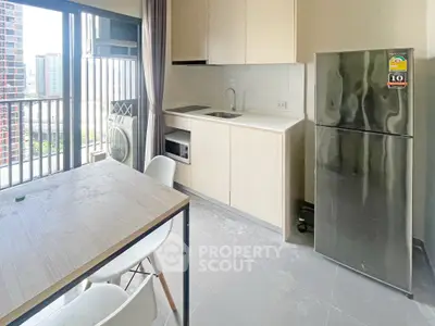 Modern kitchen with sleek cabinetry and stainless steel fridge in a high-rise apartment with city view.