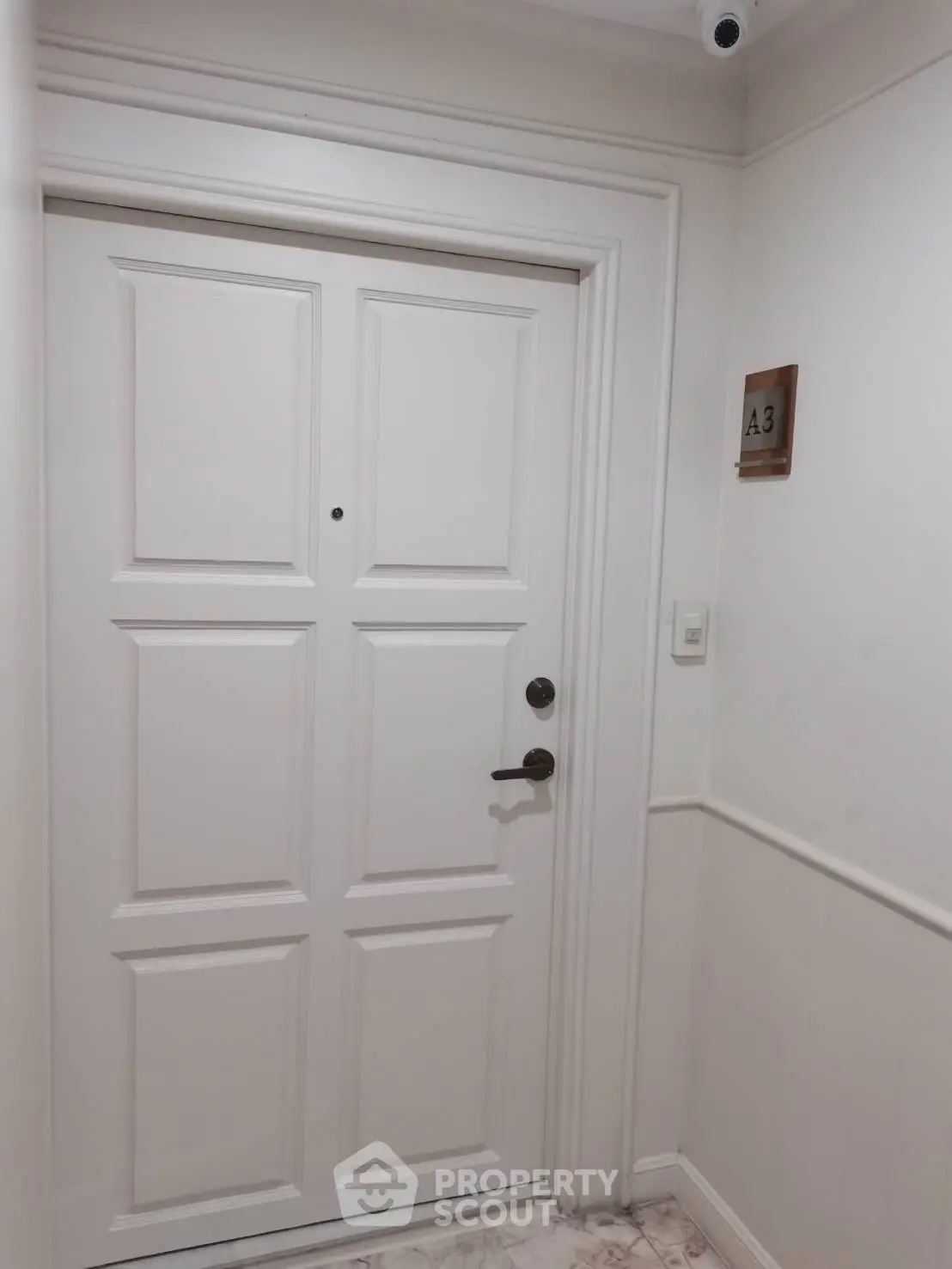Elegant white apartment door with security camera and room number A3