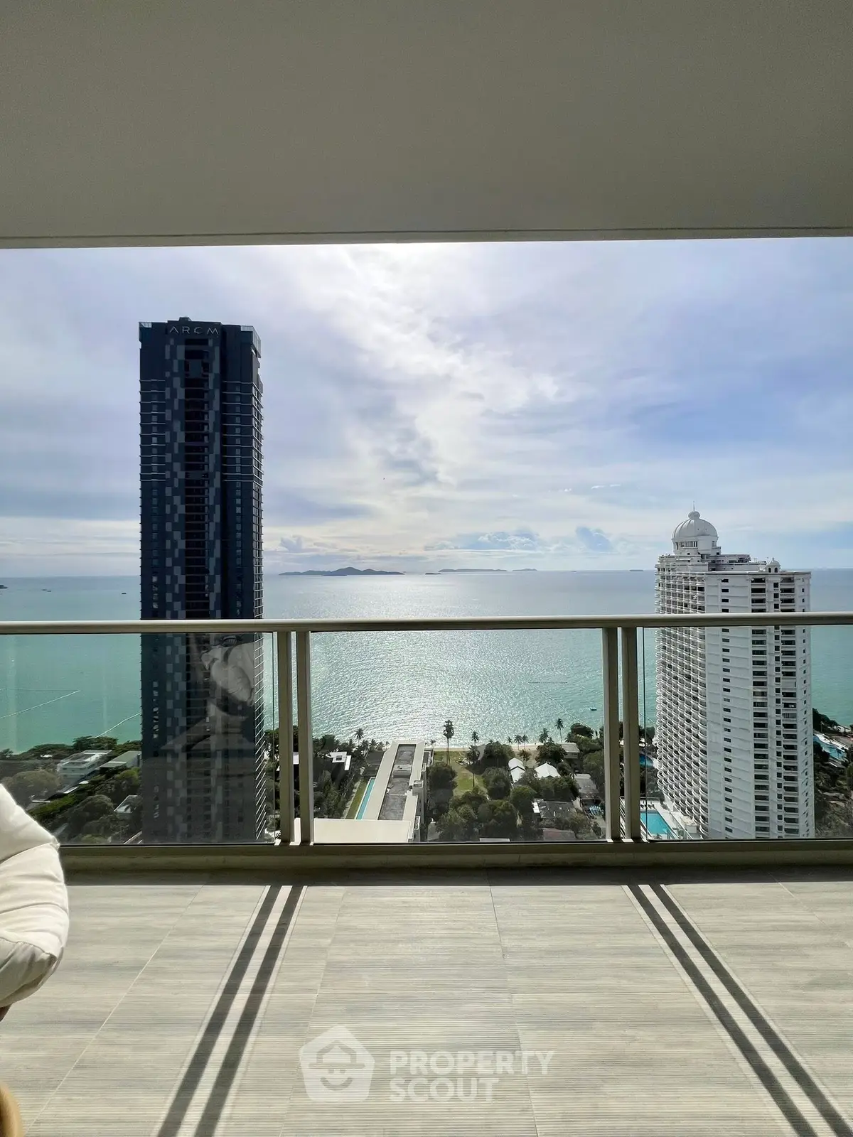 Stunning ocean view from high-rise balcony with modern railing and cityscape.