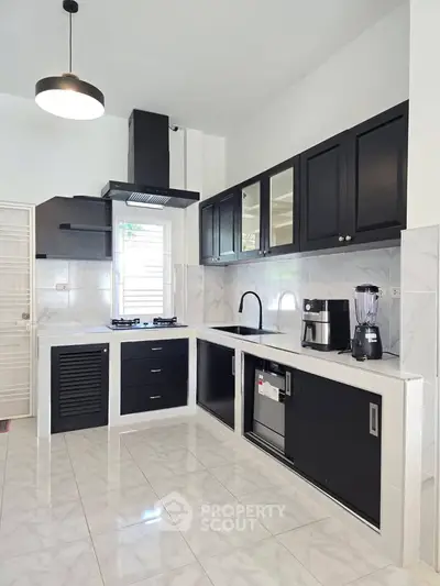 Modern kitchen with sleek black cabinets and appliances, featuring a gas stove and ample counter space.
