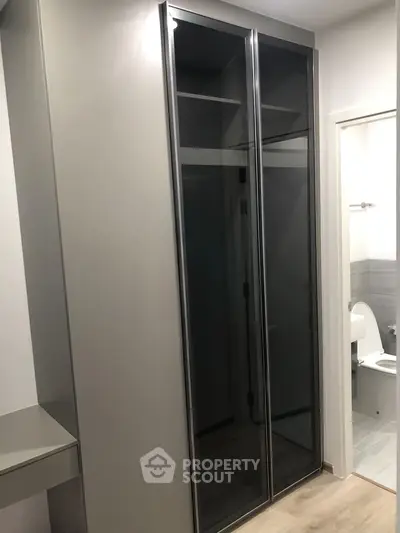 Modern interior with sleek storage and bathroom entrance, showcasing contemporary design and functionality.