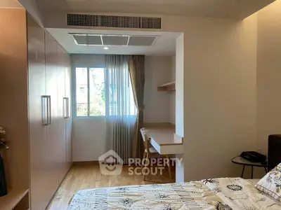 Modern bedroom with built-in wardrobe and study desk, featuring natural light and stylish decor.