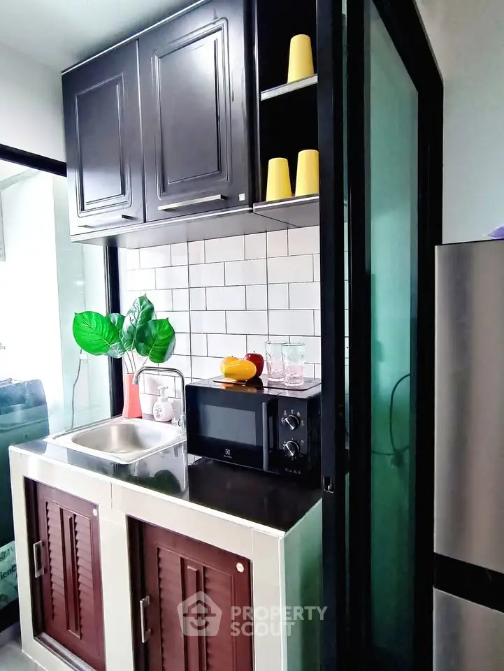Modern compact kitchen with sleek cabinetry and built-in microwave, perfect for urban living.