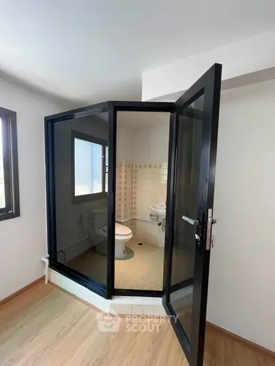Unique bathroom with glass enclosure and modern fixtures in a bright, airy space.