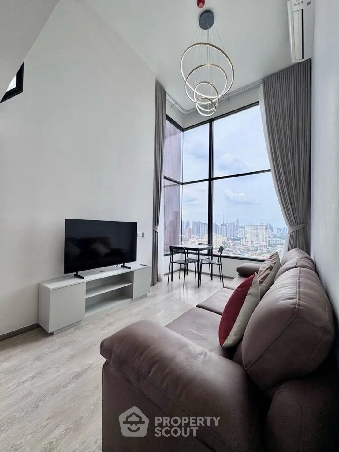 Modern living room with high ceiling and stunning city view, featuring stylish furniture and large windows.